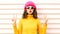 Funny happy girl blowing red lips makes air kiss wearing colorful knitted yellow sweater hat