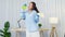 Funny happy young Asia woman holding spray microphone singing song music in modern living room while doing housekeeping in the