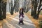 Funny horizontal shot of joyful young woman mom, rolling cute baby girl in the baby carriage, having fun, laughing and