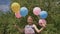 Funny idea with balloons. Cheerful and pretty girl with colorful balls attached to her hair and braids on her head.