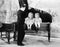 Funny image of twins sitting inside of a piano talking to a young man