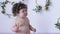 Funny infant eats cookie on photo session in studio on background of white wall with decor