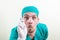 Funny inspecting doctor in green suit with laryngeal mirror in his hand