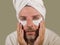 Funny isolated face portrait of young happy and attractive camp homosexual man  applying moisturizer eye patch facial product with
