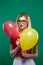 Funny Joyous Girl Hides Behind the Red and Yellow Balloons, then Suddenly Appears and Smiles Widely Looking in the