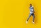 Funny jumping black guy pointing at copy space on yellow background