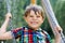 Funny kid boy having fun with chain swing on outdoor playground while being wet splashed with water