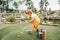 Funny kid boy playing mini golf
