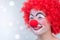 Funny kid clown laughing with red curly hair and red nose