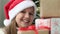 Funny kid girl wearing Santa hat holding many Christmas gifts close up