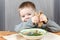 Funny kid with piece of bread and plate of soup