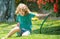 Funny kid playing with garden hose in backyard. Child having fun with spray of water. Summer outdoors activity for