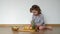 Funny kid playing with pineapple. Cut pineapple lies on a board. Little girl stacks pineapple slices.