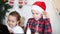 Funny kids girl and boy in Santa`s cap drinking Christmas milk, eating cookies and using a digital tablet laptop notebook. Online