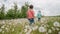 Funny kids runs, rests in dandelions meadow. Lovely brothers boys having fun, playing outdoors, explores plants, nature