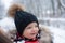 Funny laughing baby in winter outside. Cute toddler kid in a warm snowsuit and hat discovered winter forest. Snow, red