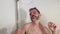 Funny lifestyle shot of young attractive and happy man with beard dancing and singing in the shower carefree and crazy at bathroom