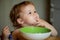 Funny little baby in the kitchen eating with fingers from plate. Child nutrition concept.