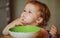 Funny little baby in the kitchen eating with fingers from plate. Child nutrition concept.