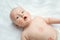 Funny little baby playing on a white knitted blanket in a sunny nursery. adorable child with red kisses on the skin. Infant nappy