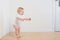 Funny little  baby takes first steps on wooden floor