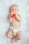 Funny little baby wearing a diaper playing on a white knitted blanket in a sunny nursery. adorable child. Infant nappy change and