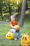 Funny little boy in a fairy hat sits on a pumpkin and prepares for Halloween