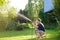 Funny little boy with his father playing with garden hose in sunny backyard. Preschooler child having fun with spray of water