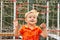 Funny little boy on playground with a grid of football gate. playing child on sports ground.