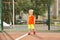 Funny little boy on playground with a grid of football gate. playing child on sports ground.