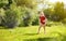 Funny little boy playing with garden sprinkler in sunny backyard