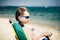 Funny little child with stylish sunglasses sitting in beach tanning