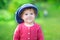 Funny little girl in big knitted hat in the garden