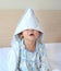 Funny little girl with blanket cover on head lying on the bed