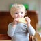 Funny little girl eating sandwich at home