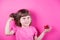 Funny little girl holding pretty spotted gift box in her hands on bright pink background