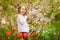 Funny little girl near with almond bush and tulips
