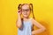 Funny little girl of preschool age corrects glasses. A child on a yellow background