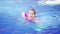 a funny little girl swims in inflatable armbands in a pool