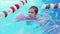 a funny little girl swims in inflatable armbands in a pool near the buoys.