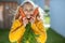 Funny little girl in yellow posing with bunch of carrots during gathering harvest