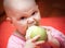 Funny little hungry baby eats green apple