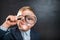 Funny little kid boy looking through a magnifying glass. Big eye. Back to school. Child curiosity