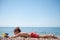 Funny little lying caucasian boy with water toy gun and goggles aiming on summer sea beach during travel vacation