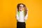 Funny Little Schoolgirl Keeping Fingers Crossed Over Yellow Studio Background