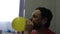 Funny man with a beard and mustache inflates a yellow balloon with his mouth
