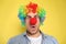 Funny man with clown nose and rainbow wig on background. April fool`s day