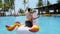 Funny man having fun, dancing on floating inflatable unicorn, tropical vacation