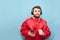 Funny man in a red jacket and a smartphone in his hand listening to music on headphones on a blue background. Bearded man in the