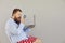 Funny man in red shorts with a laptop increases magnifying information on a gray background. Concept of online